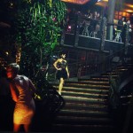 A model wearing a George Wu dress with a sheer black top and fluffy black skirt descends a staircase.