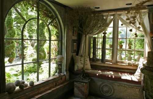 A photo of two adjacent walls with two big old windows with a gorgeous view to a green garden.