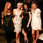 Designer Anna Campbell stands with three models, all wearing black or white variations on lace, layered feminine dresses.