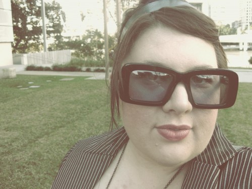 An overly edited photo of Natalie wearing a pair of sunglasses with heavy black squarish frames.