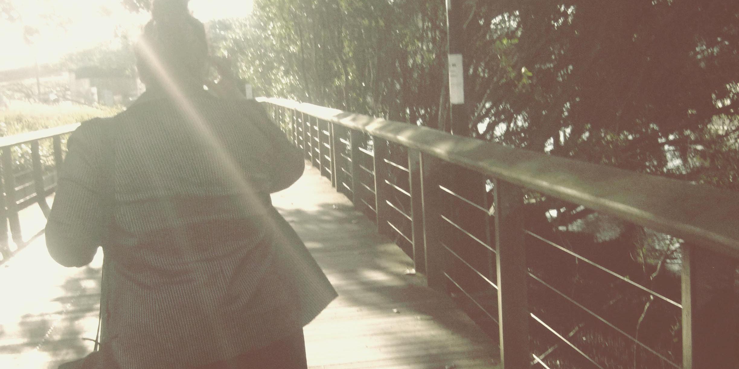 Photo of Natalie's silhouette, she's walking away from the camera along a wooden walkway into a solar flare.