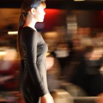 The profile of a model in a black dress walking.