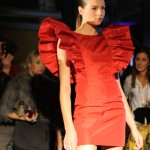 Model wearing a red dress with wide and spectacular ruffled sleeves.