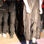 Model wearing a long sheer black dress with diagonal seams and detailing.
