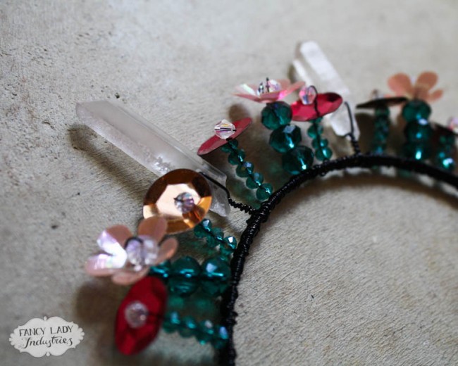 A tiara that looks like short flowers made up of green crystals and vintage sequins accented with crystal points.