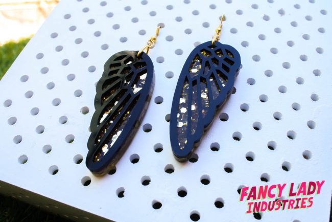 Some bird wing dangly earrings made from laser cut black and gold glitter acrylic available on Fancy Lady Industries.