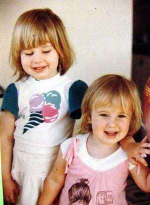 Old photo from 1985 of two little girls, I'm the taller one with an ice cream shirt, and my sister is the smaller one wearing a pink dress.