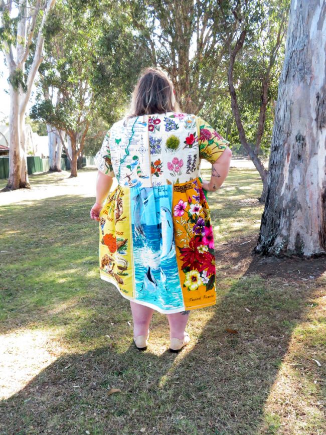 A photo of the back of me, displaying the various tea towels including a map, native flowers, dolphins and animals.